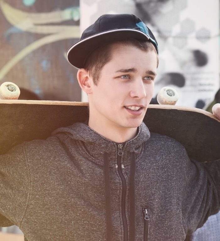 teen boy with skateboard outside