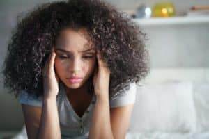 troubled teenager with head in hands thinking about how trauma can affect teenage brain development