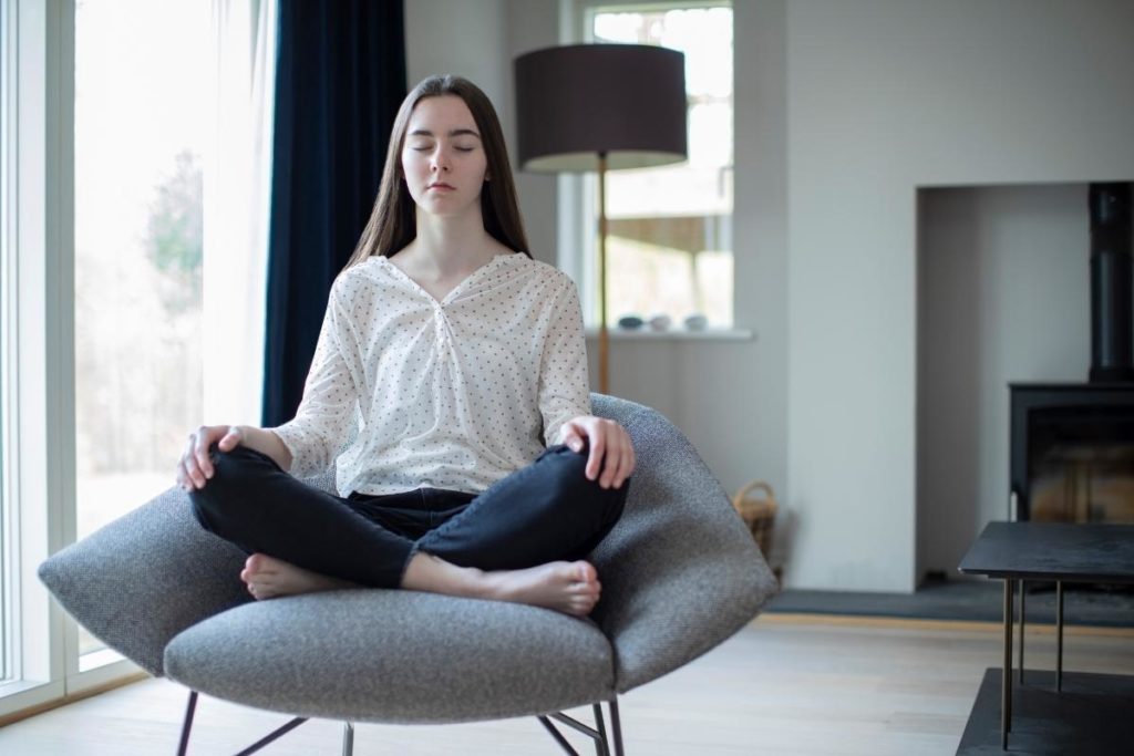 woman sitting on chair in well-lit room wondering will meditation therapy help my teen
