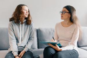 female therapist sitting on couch next to female patient answering the question is there a correct way to heal from trauma