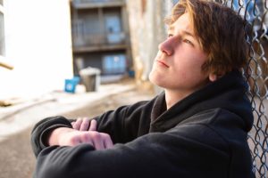 young man seated and reflecting upon how does bullying influence mental health