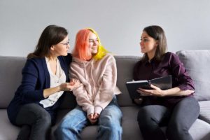 female therapist explaining to mother and teenage daughter what is dialectical behavior therapy and how does it benefit teens