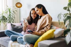 mother sitting with teen daughter on couch and discussing 5 fun activities to improve your teens mental health