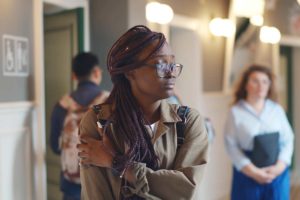 teenage girl standing in high school hallway looking anxious and wondering how to improve mental health as a teenager
