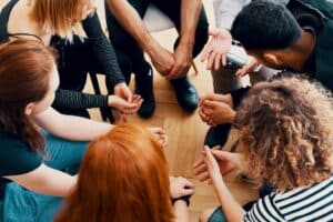 group of teenagers seated in a circle enjoying the benefits of crisis interventions during group therapy.