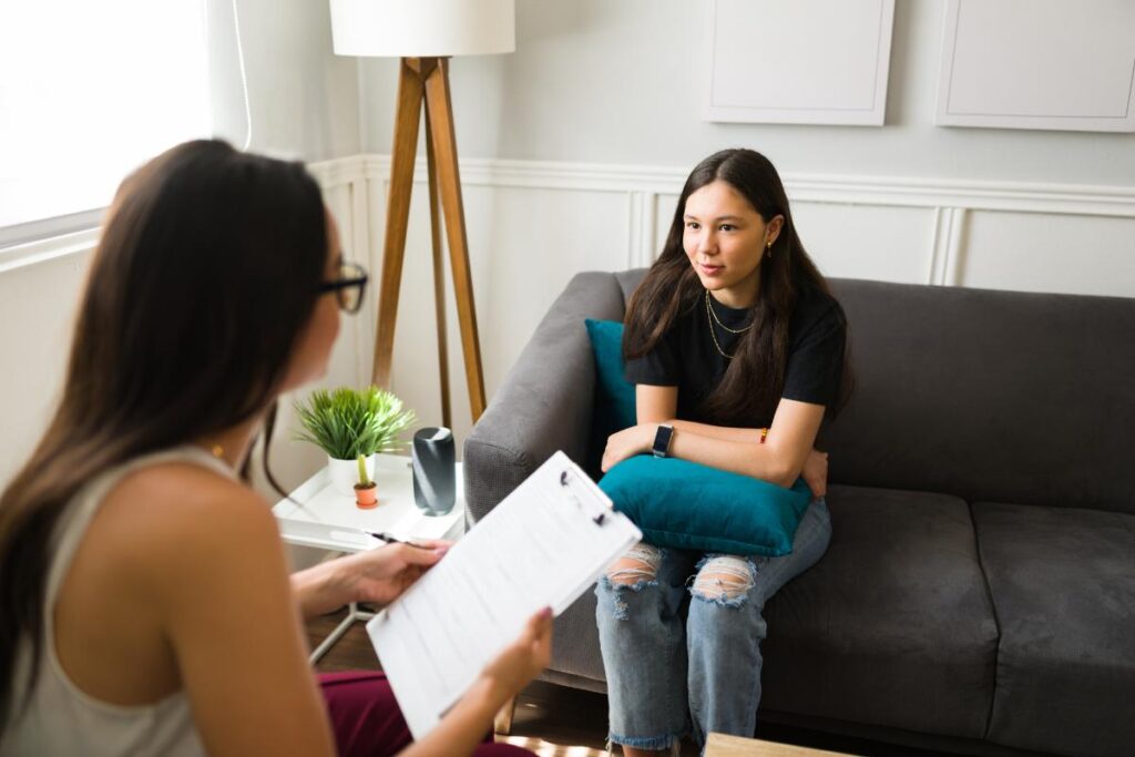 teenage girl having serious conversation with female therapist about the benefits of teen relationship counseling