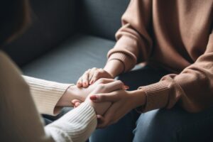 therapist supportively clasping hands of teenager as they explain the benefits of trauma therapy.