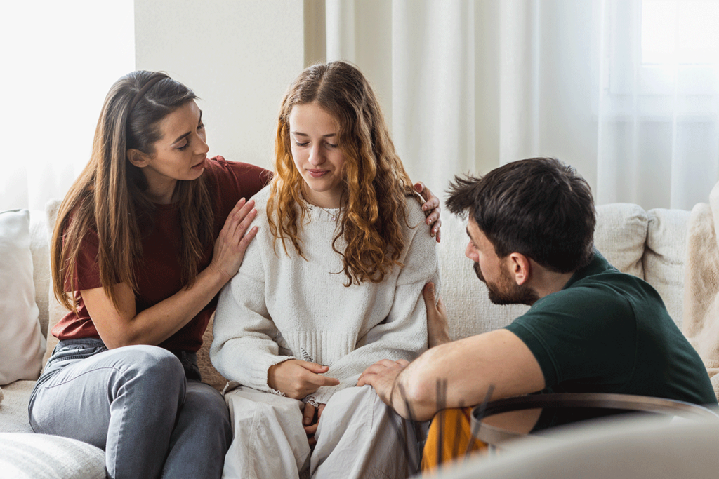 parent and therapist talking with serious looking teen girl about the family therapy benefits for teens