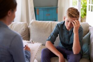 therapist patiently explaining 5 mental health activities for teens to adolescent boy.