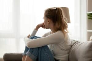 teenage girl seated on couch looking pensive as she struggles with how to heal from trauma