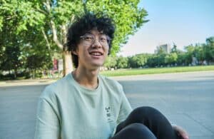 teen boy in white crew neck tee smiling while sitting outside
